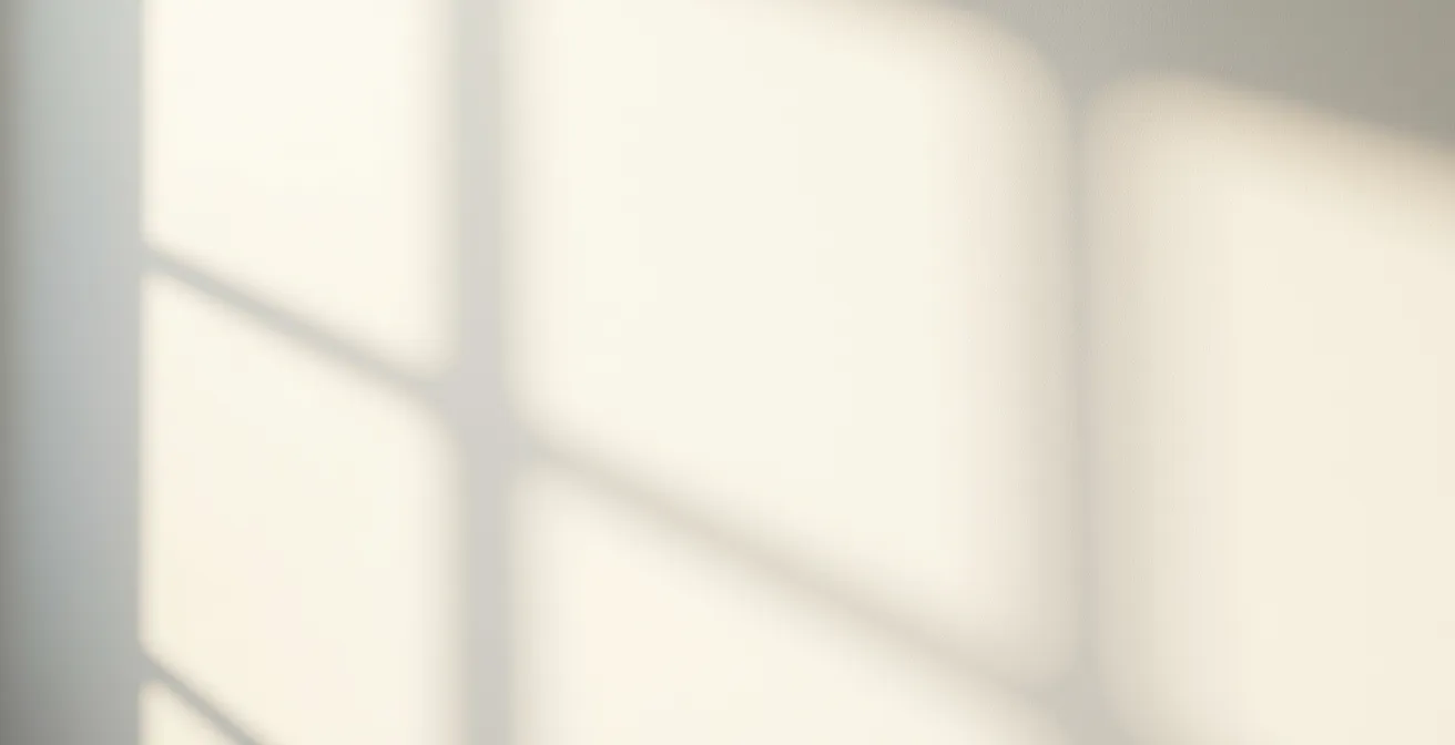 Mur peint en blanc cassé avec variations subtiles de lumière naturelle créant une atmosphère chaleureuse